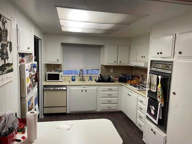 a kitchen with cabinets stainless steel appliances and wooden floor