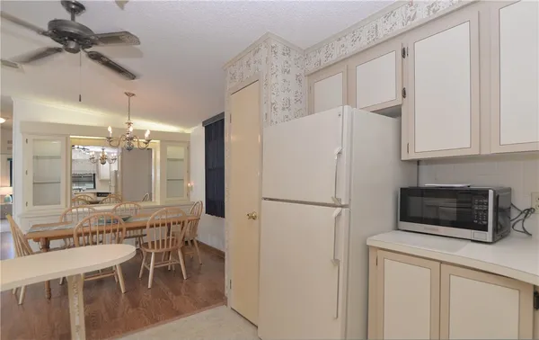 a white kitchen with stainless steel appliances a refrigerator a stove a microwave oven with a dining table and chairs