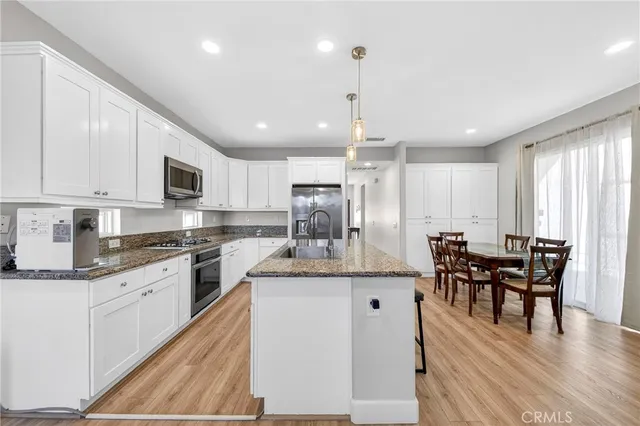 a kitchen with kitchen island a counter top space a sink stainless steel appliances and cabinets