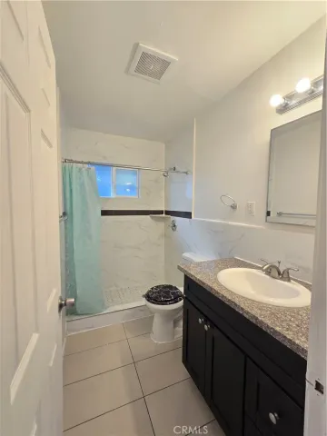 a bathroom with a granite countertop sink a toilet a mirror and vanity