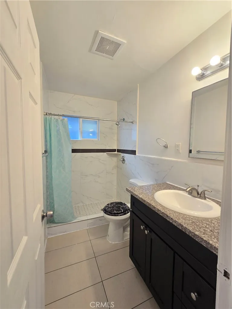 11323 Schmidt Road El Monte, CA 91733 - Photo 12 of 12 a bathroom with a granite countertop sink a toilet a mirror and vanity