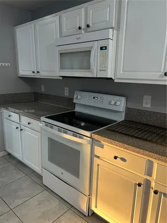 a kitchen with granite countertop white cabinets and black appliances