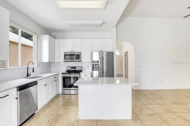 a large kitchen with stainless steel appliances granite countertop a stove a sink and a refrigerator