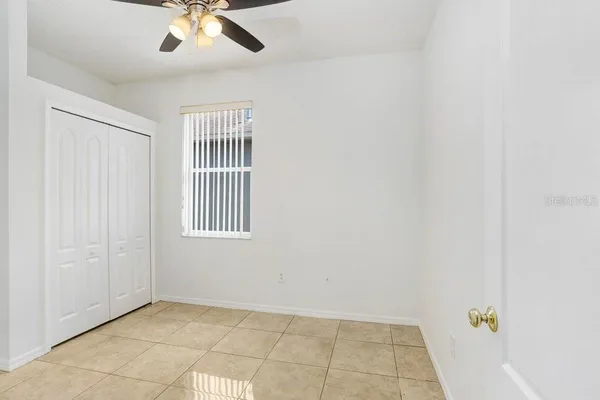 an empty room with a chandelier fan and windows