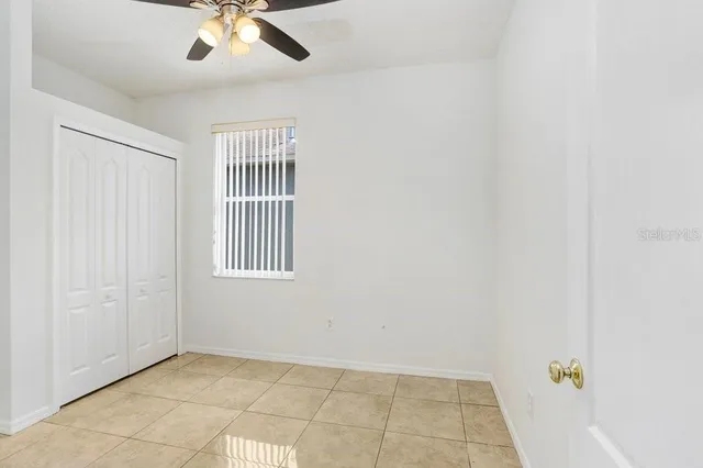 an empty room with a chandelier fan and windows