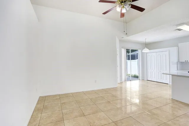 a view of an empty room and chandelier fan