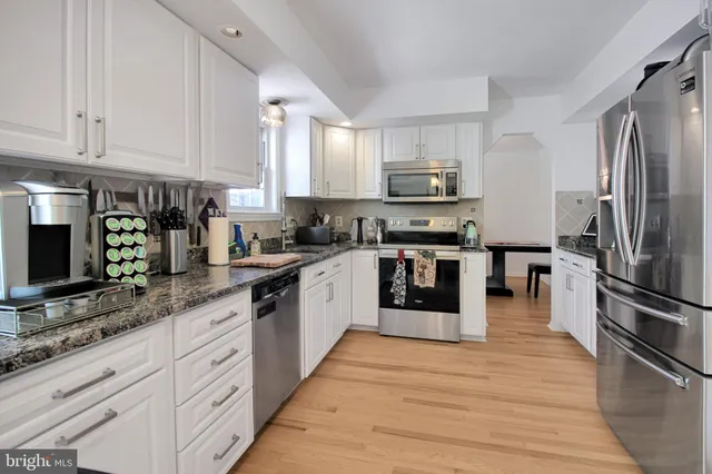 a kitchen with stainless steel appliances granite countertop a refrigerator and a stove top oven