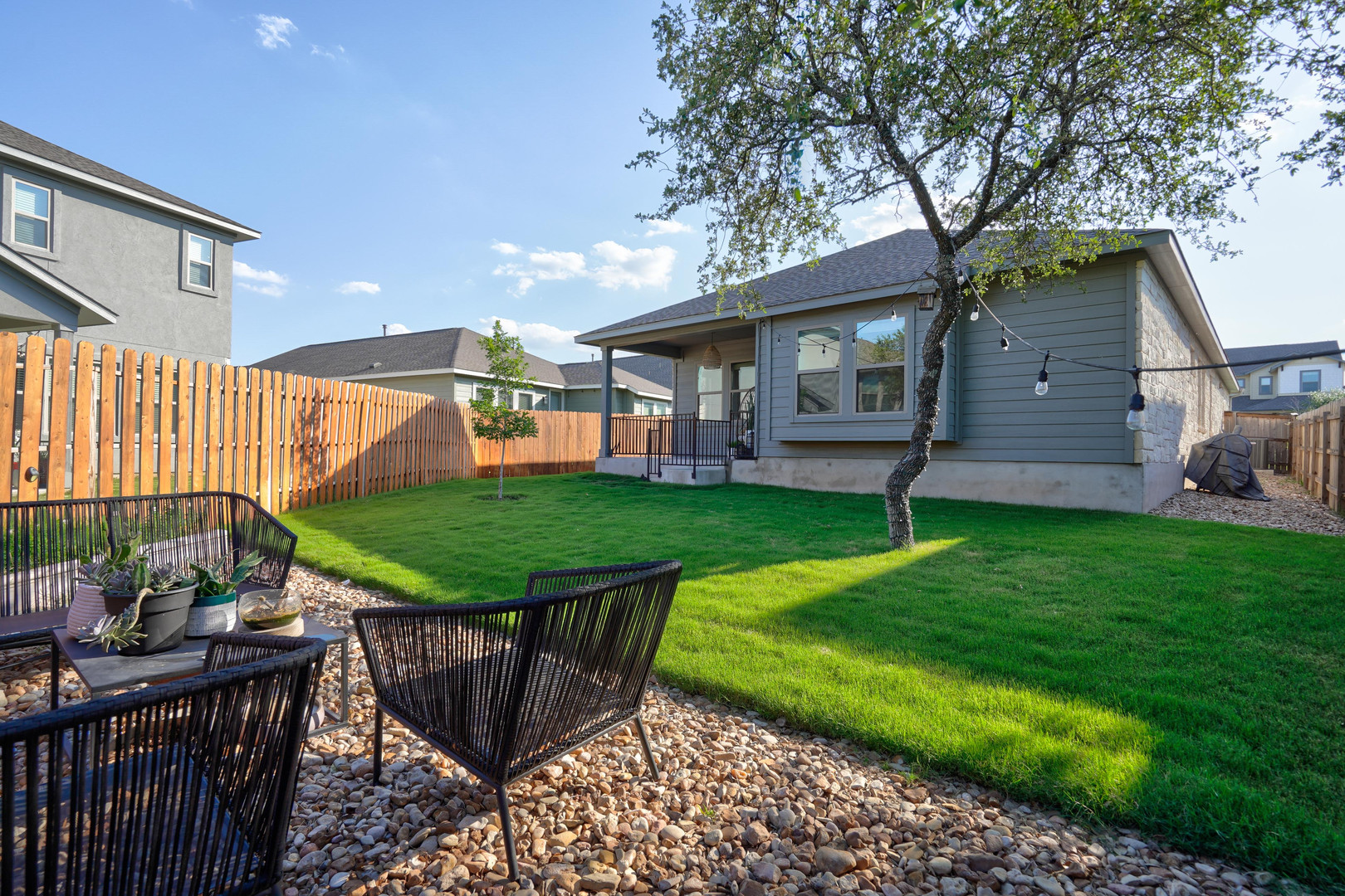 2240 Ringstaff Road Leander, TX 78641 - Photo 24 of 25 Expansive backyard featuring a manicured lawn, a mature tree, and a covered patio area with string lighting