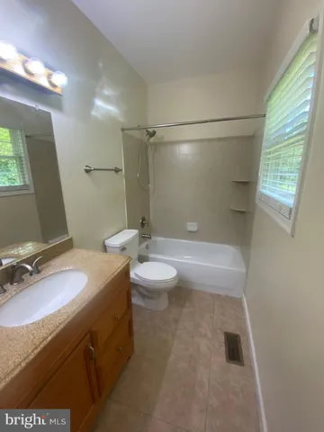 a bathroom with a granite countertop sink a toilet a mirror and shower