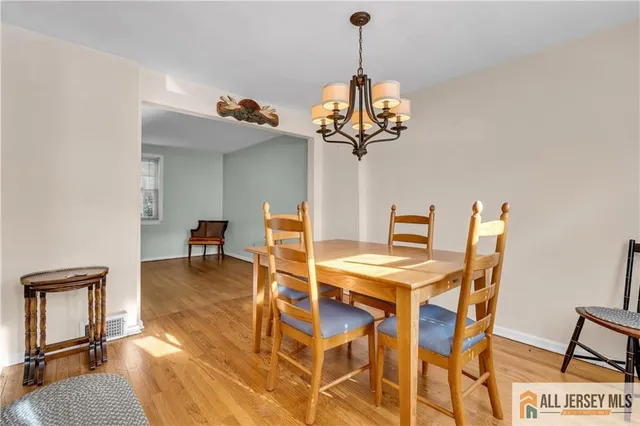 a view of a dining room and livingroom with furniture wooden floor a chandelier
