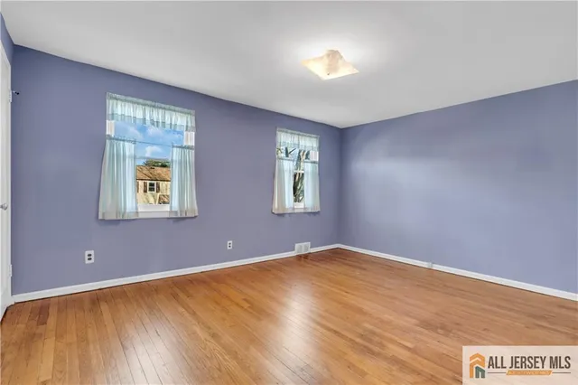 a view of an empty room with window and wooden floor