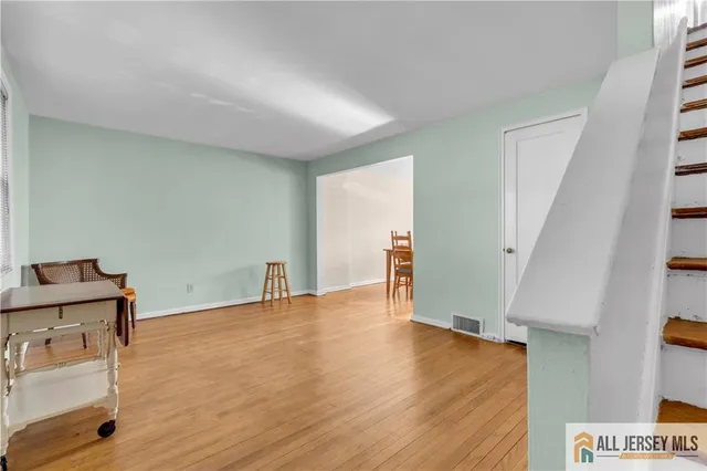 a view of an empty room with wooden floor and stairs