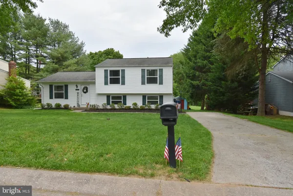 a front view of a house with a garden and trees
