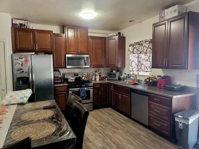 a kitchen with granite countertop wooden cabinets a refrigerator and a stove top oven