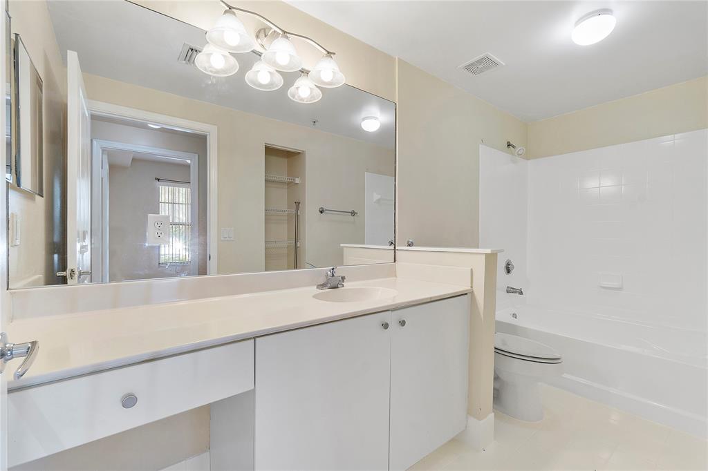 6020 West Sample Road, Unit 103 Coral Springs, FL 33067 - Photo 14 of 20 a bathroom with a granite countertop sink a toilet and a mirror