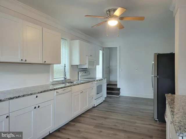 a kitchen with granite countertop white cabinets and white appliances