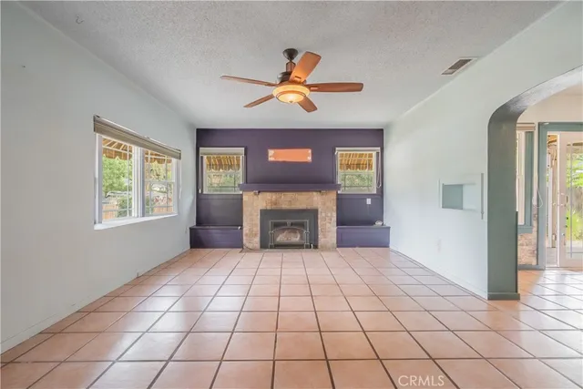 a view of an empty room with window and chandelier fan