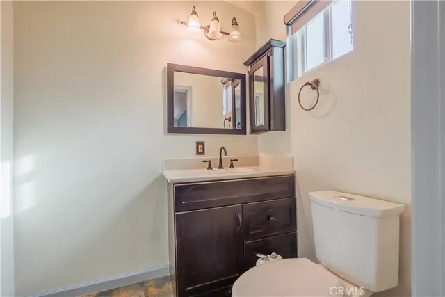 a bathroom with a toilet a sink a mirror and vanity