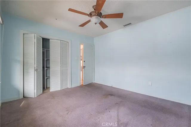 an empty room with closet and fan