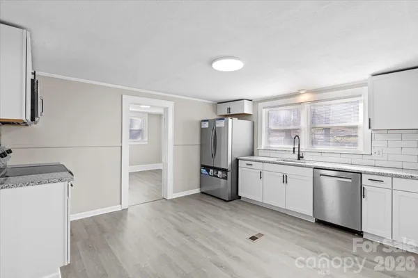 a kitchen with a sink a refrigerator and wooden floor
