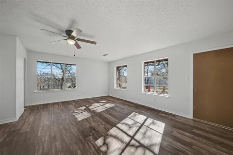 a view of empty room with wooden floor and fan