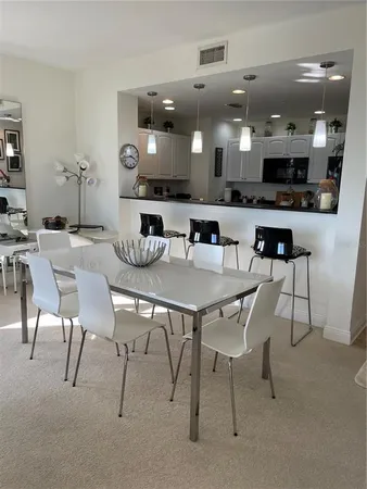 a kitchen with stainless steel appliances kitchen island granite countertop a dining table chairs and a refrigerator