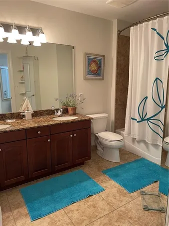 a spacious bathroom with a granite countertop sink a toilet and a mirror