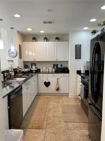 a kitchen with stainless steel appliances granite countertop a sink a stove a refrigerator a microwave oven with white cabinets and wooden floor