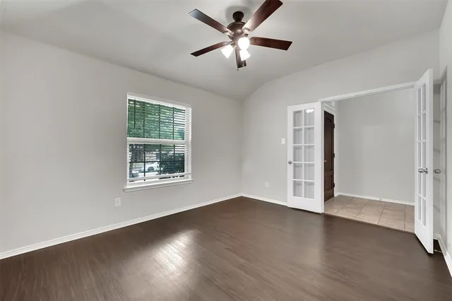 a view of an empty room with wooden floor and a window