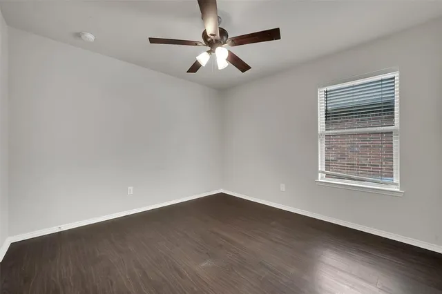 an empty room with wooden floor chandelier fan and windows