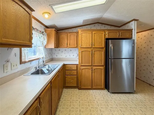 a kitchen with stainless steel appliances granite countertop a refrigerator sink stove and cabinets