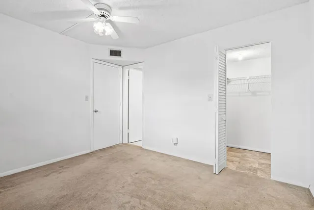 an empty room with a ceiling fan and a window