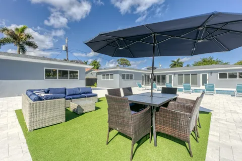 a view of a patio with couches table and chairs under an umbrella