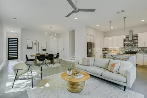 a living room with furniture kitchen view and a chandelier