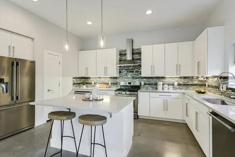 a kitchen with stainless steel appliances granite countertop a stove a sink and white cabinets