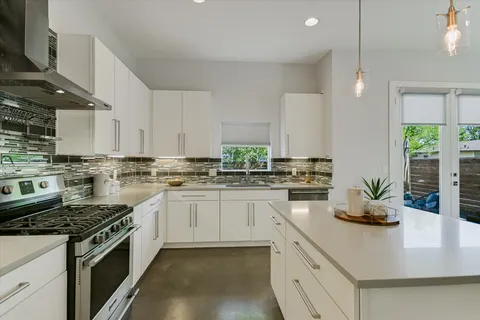 a kitchen with stainless steel appliances granite countertop a sink a stove and a wooden floors
