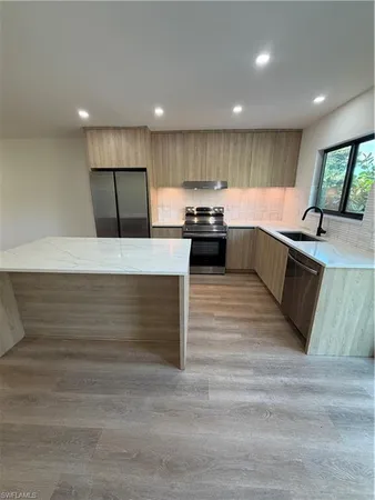 a large kitchen with stainless steel appliances kitchen island a large counter top and a stove