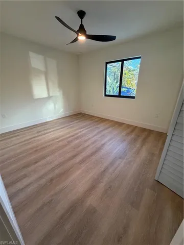 an empty room with wooden floor ceiling fan and windows