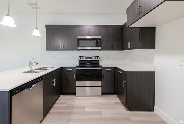 4661 Poplar Way, Unit R303 Mapleton, UT 84664 - Photo 11 of 17 Kitchen featuring a peninsula, stainless steel appliances, dark wood finish cabinets, light wood finished floors, and pendant lighting