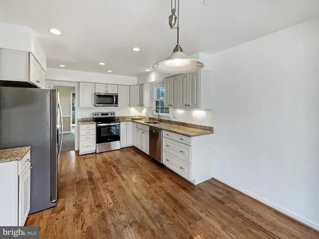 a kitchen with stainless steel appliances granite countertop a sink a stove top oven a refrigerator with island and chairs