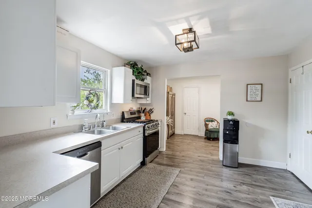a kitchen with a sink dishwasher a stove and white cabinets