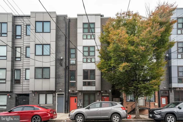 a front view of a building with lot of cars and trees