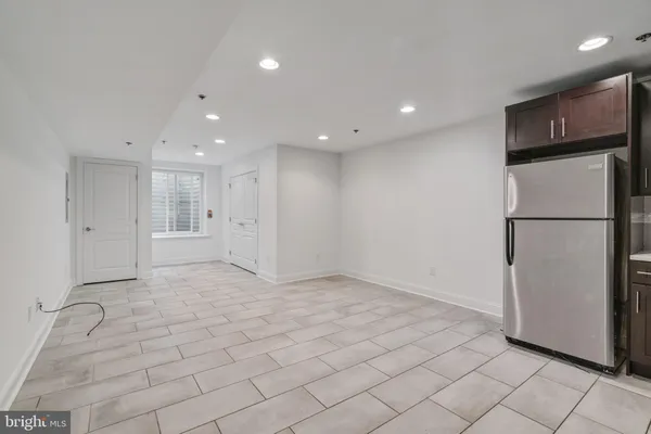 a view of a refrigerator in kitchen and an empty room