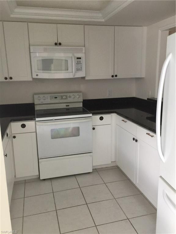5651 Rattlesnake Hammock Road, Unit C108 Naples, FL 34113 - Photo 4 of 14 a kitchen with granite countertop white cabinets and white appliances
