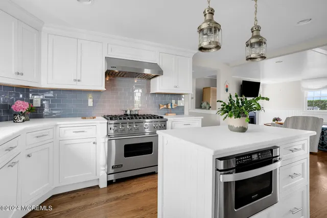 a kitchen with stainless steel appliances a stove a sink a microwave a dining table and chairs