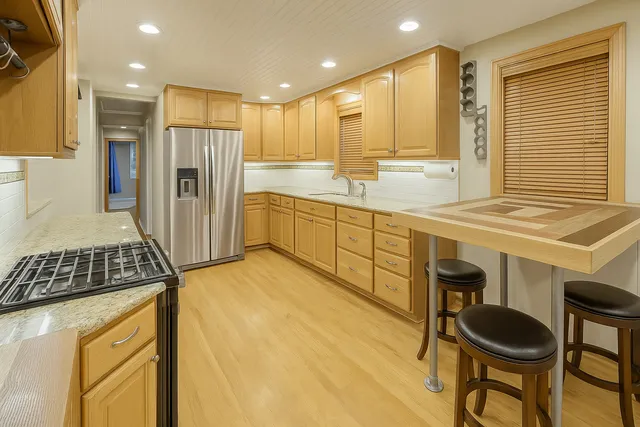 a kitchen with stainless steel appliances granite countertop a sink and a refrigerator