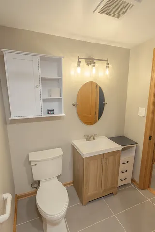 a bathroom with a toilet mirror vanity and sink