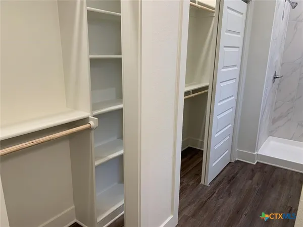 a walk in closet with wooden floor