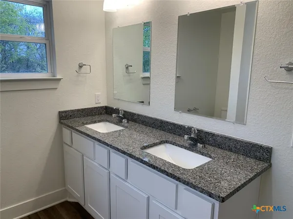 a bathroom with a granite countertop sink and a mirror