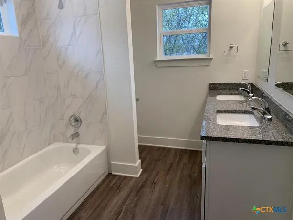 a bathroom with a granite countertop sink and a bathtub